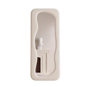 Cream textured full-length mirror with an irregular wavy frame, reflecting a neutral interior with a mantel and bust sculpture, showcasing a tall elegant silhouette