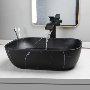 Luxurious black ceramic vessel sink with subtle white veining and a matte black waterfall faucet, set on a white countertop with a modern bathroom mirror and toothbrushes nearby.