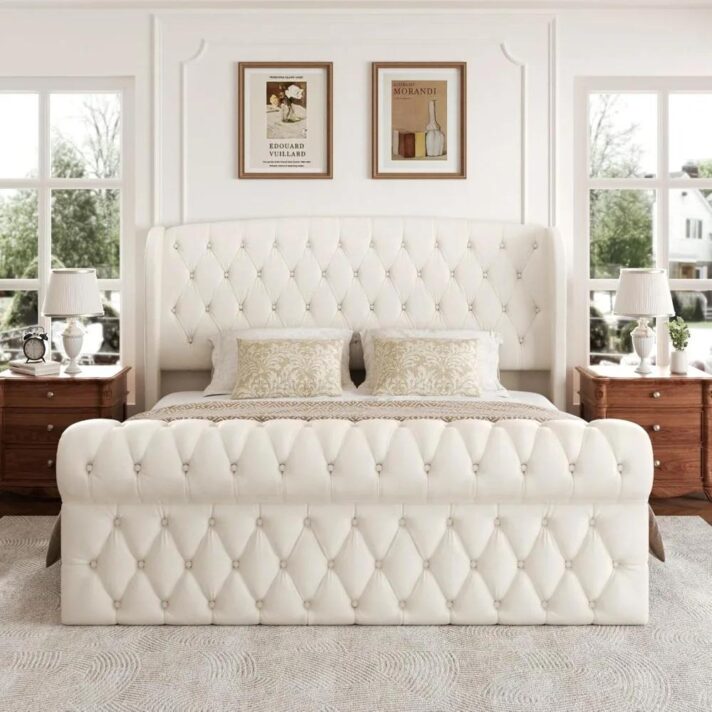 Luxurious white king-size platform bed with a tall tufted wingback headboard in soft chenille upholstery, flanked by matching wooden nightstands and classic lamps.