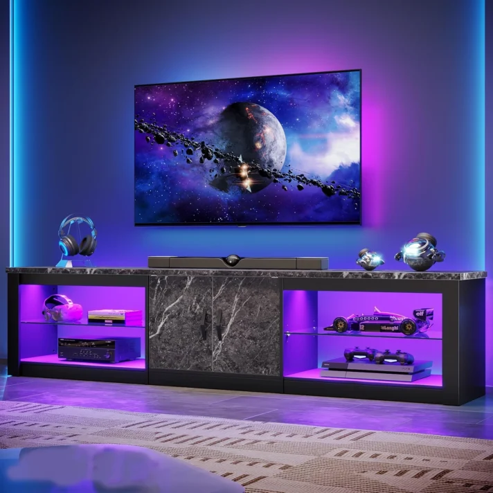 Verra Luxe Home 80-inch TV stand with a dark marble cabinet, blue and purple LED backlighting, a large flat screen TV, and gaming accessories such as a PlayStation 5 and Nintendo Switch on display.