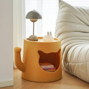 Yellow round Modern Cat Nest Bedside Coffee Table by Verra Luxe Home, featuring a cat-shaped cutout, a small lamp, and a bunny figurine on top, placed beside a light sofa.