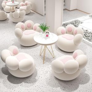 Group of white rounded lounge seats with soft pink inner cushions around a white marble-topped table in a bright, minimal Nordic-inspired interior.
