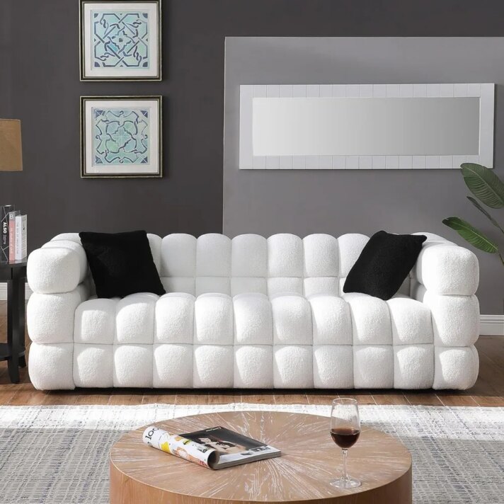 White Sherpa boucle deep-seat sofa with a cloud-like tufted design and two black accent pillows set against a modern living room backdrop, reflecting Verra Luxe Home styling.