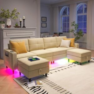 Beige oversized U-shaped sectional couch with built-in RGB LED lighting under the base, two ottomans, a charging station, and a modern living room setting.