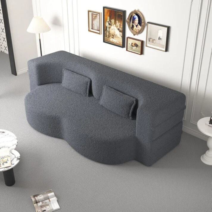 Gray curved sofa bed with plush textured fabric, matching cushions, showcased in a stylish living room scene from Verra Luxe Home, highlighting the 78” convertible design