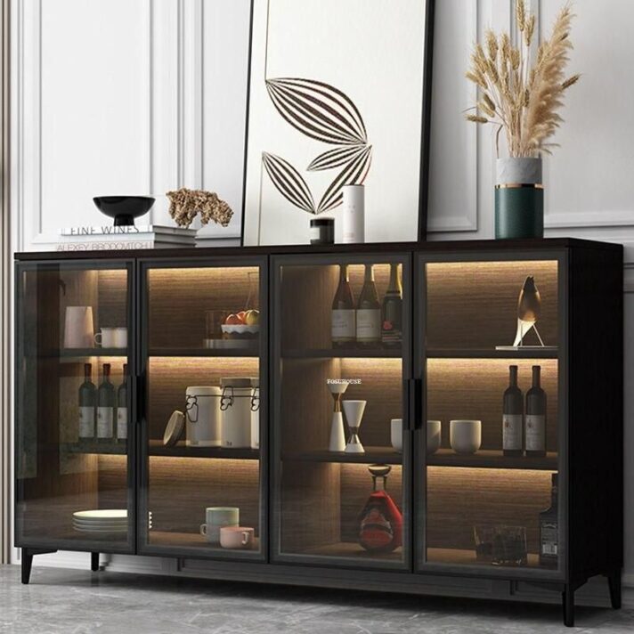 Verra Luxe Home dark glass-fronted solid wood sideboard with warm interior lighting, displaying bottles, ceramics, and decorative accents in a minimalist modern living space.