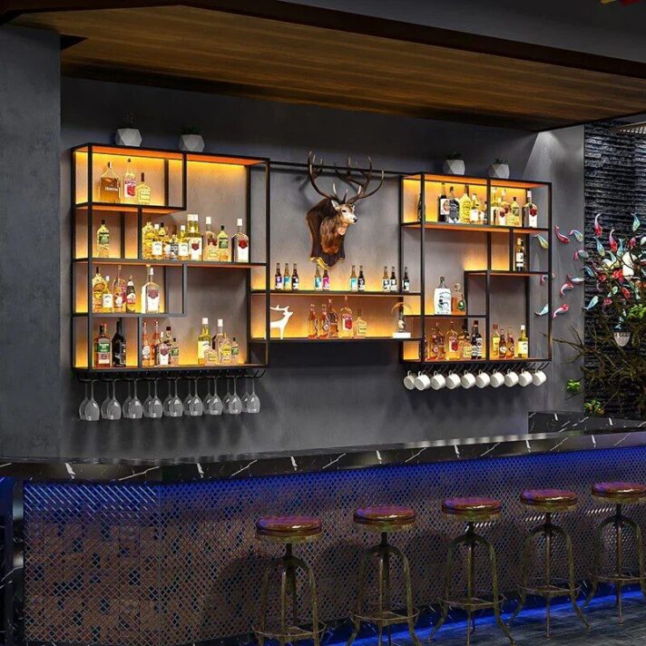 Verra Luxe Home Modern Illuminated Wall-Mounted Wine Cabinet on a dark bar wall with warm-lit metal shelves, assorted liquor bottles, and a deer head centerpiece.