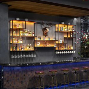 Modern illuminated wall-mounted wine cabinet display with warm backlit metal shelves, showcasing bottles and glassware beneath a deer head focal decor, at Verra Luxe Home