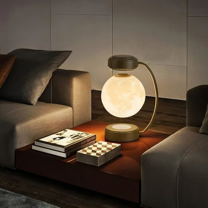 Round glass globe lamp with a gold arc base glowing softly on a coffee table beside a gray sofa, in a modern living room setting.
