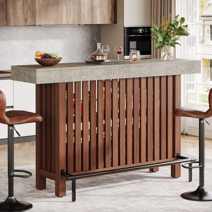 63-Inch Modern Home Bar Unit featuring dark brown vertical slats, concrete top, and two-tier open shelving with a footrest. Paired with brown leather stools and a sleek modern kitchen setting.