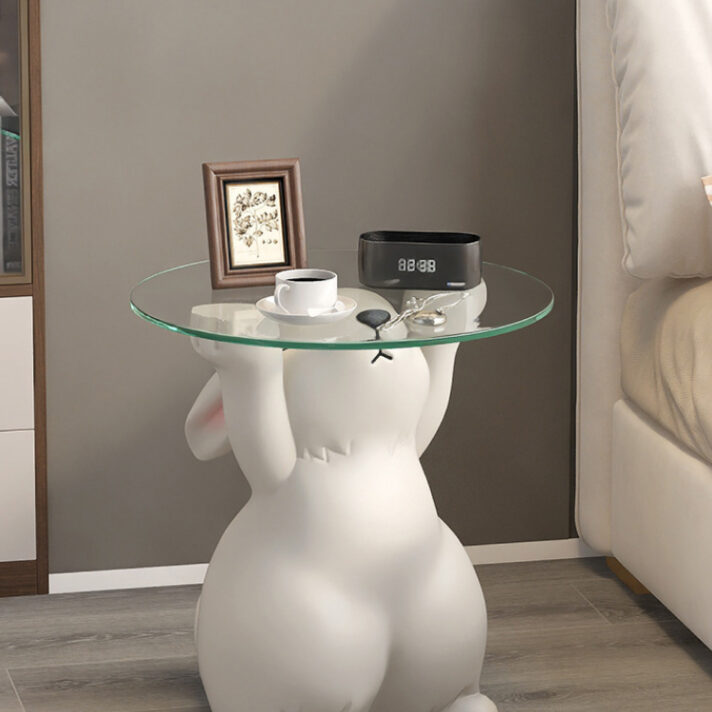 White resin rabbit statue with a round glass tabletop, a Nordic-style side table featuring a bunny figure and decorative items on top
