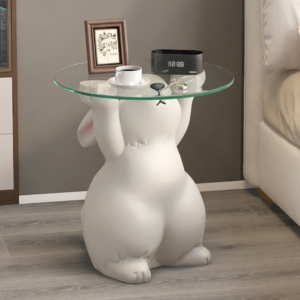 White rabbit statue side table with a round glass top, glossy resin finish, and a small framed art piece on the tabletop in a modern living room setting
