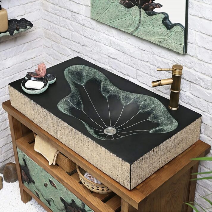 Black rectangular resin washbasin with lotus leaf pattern and a brass faucet, beige textured sides, mounted on a wooden vanity.