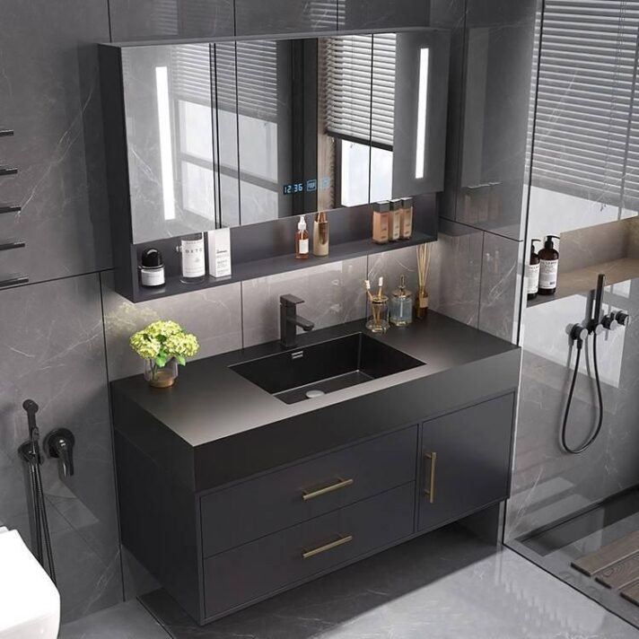Modern minimalist black oak bathroom vanity with integrated mirror light, black matte cabinet, and gold hardware surrounding a sleek sink setup.