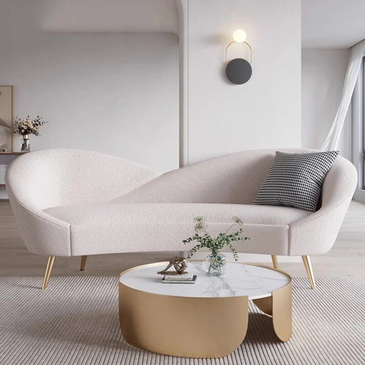 Versatile Nordic Love Seat, a 3-Seater Lazy Sofa in soft pink boucle fabric with a curved silhouette and gold tapered legs, placed in a modern living room